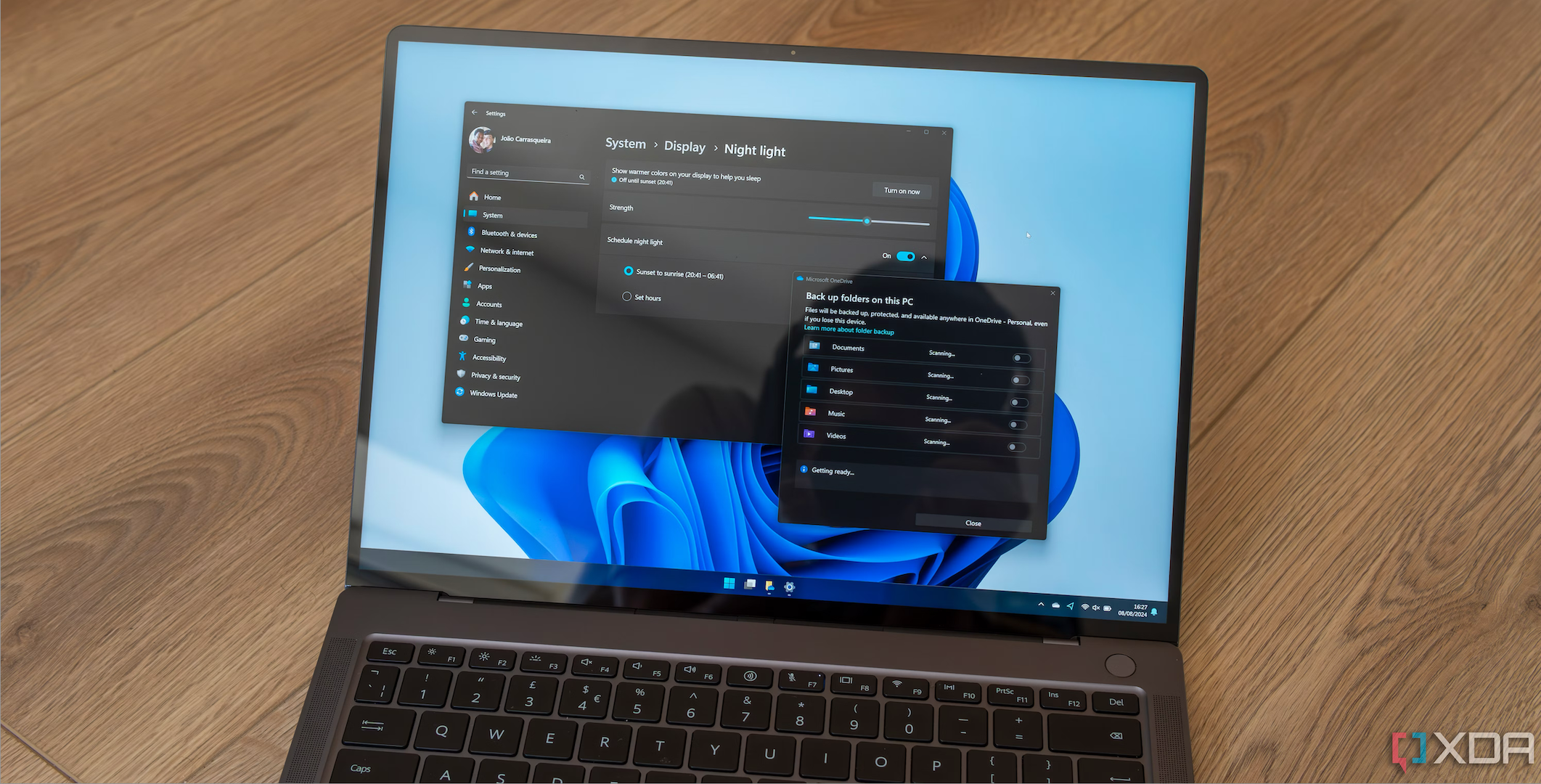 A Windows 11 laptop displaying the settings for night light and OneDrive backups