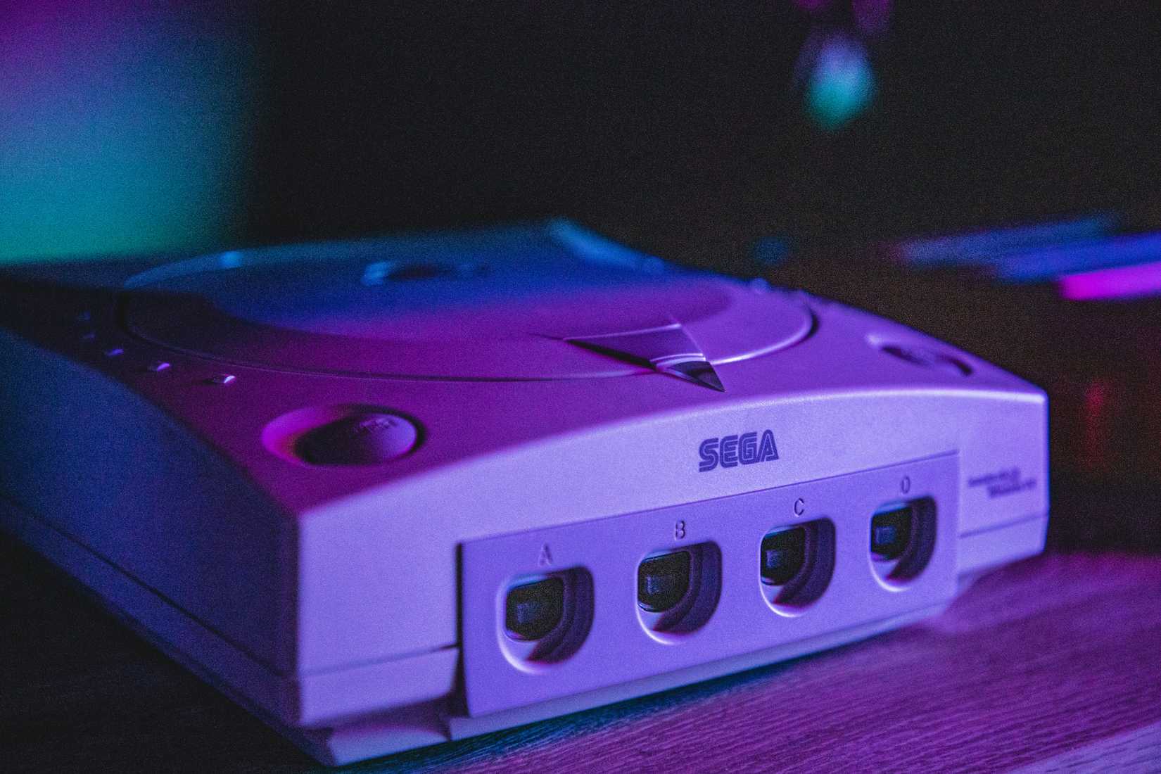 A Sega Dreamcast in moody purple lighting.