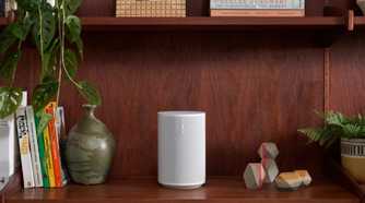 sonos era 100 speaker in white on a bookshelf