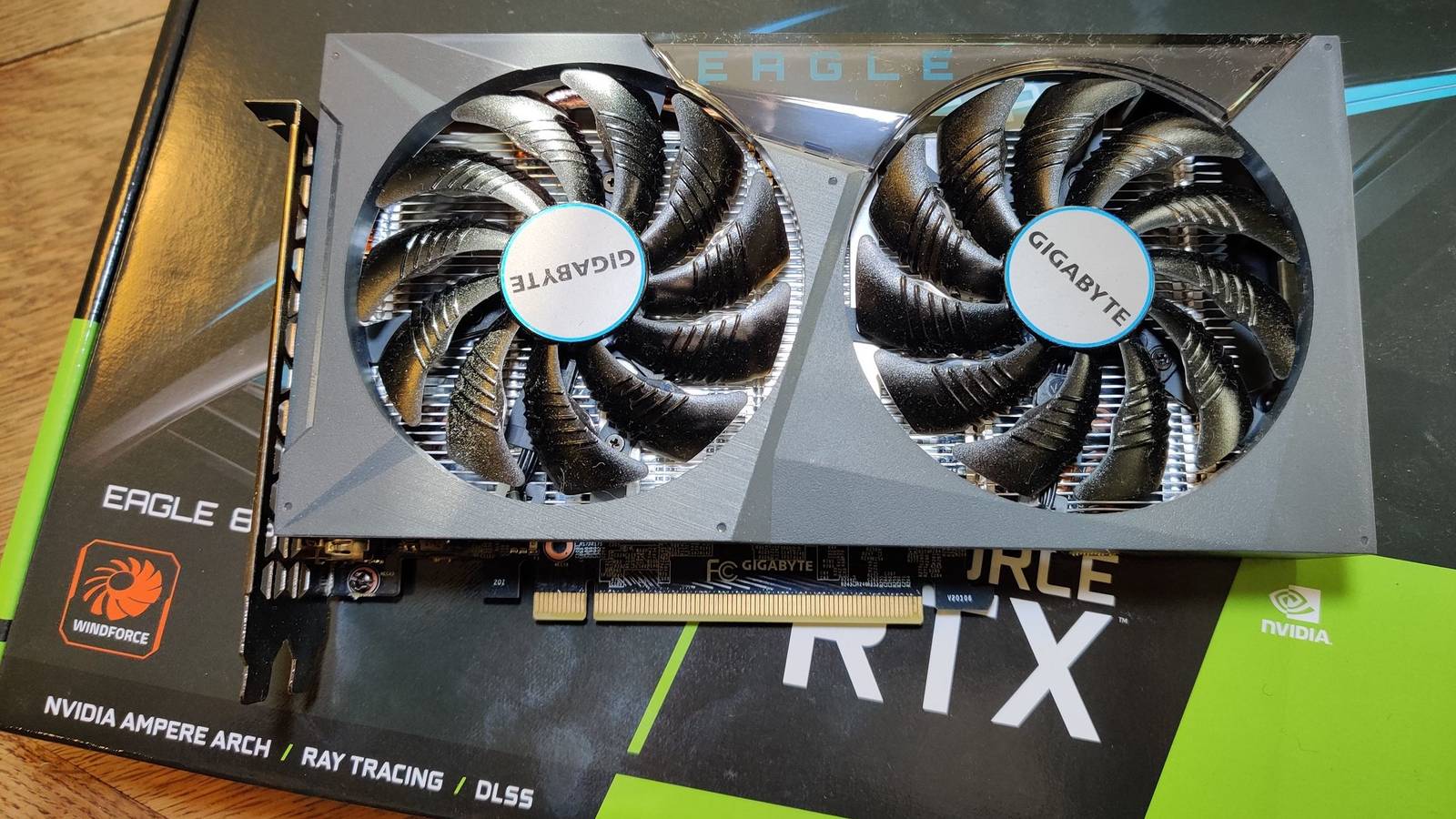 A grey graphics card with two fans placed on its retail box