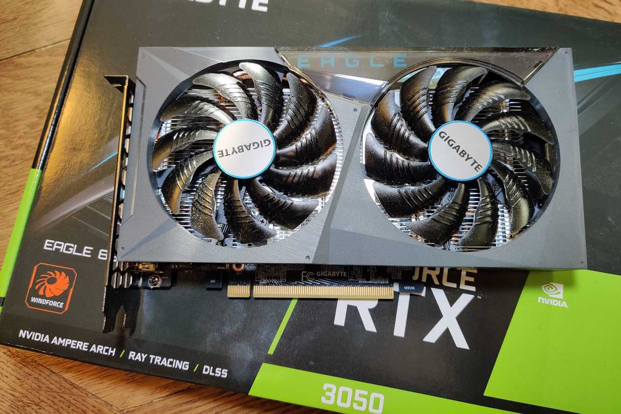 A grey graphics card with two fans placed on its retail box