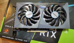 A grey graphics card with two fans placed on its retail box