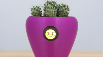 A purple flower pot with a sick emoji on it