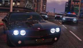 Screenshot from Grand Theft Auto V of three police cars chasing one black car on highway