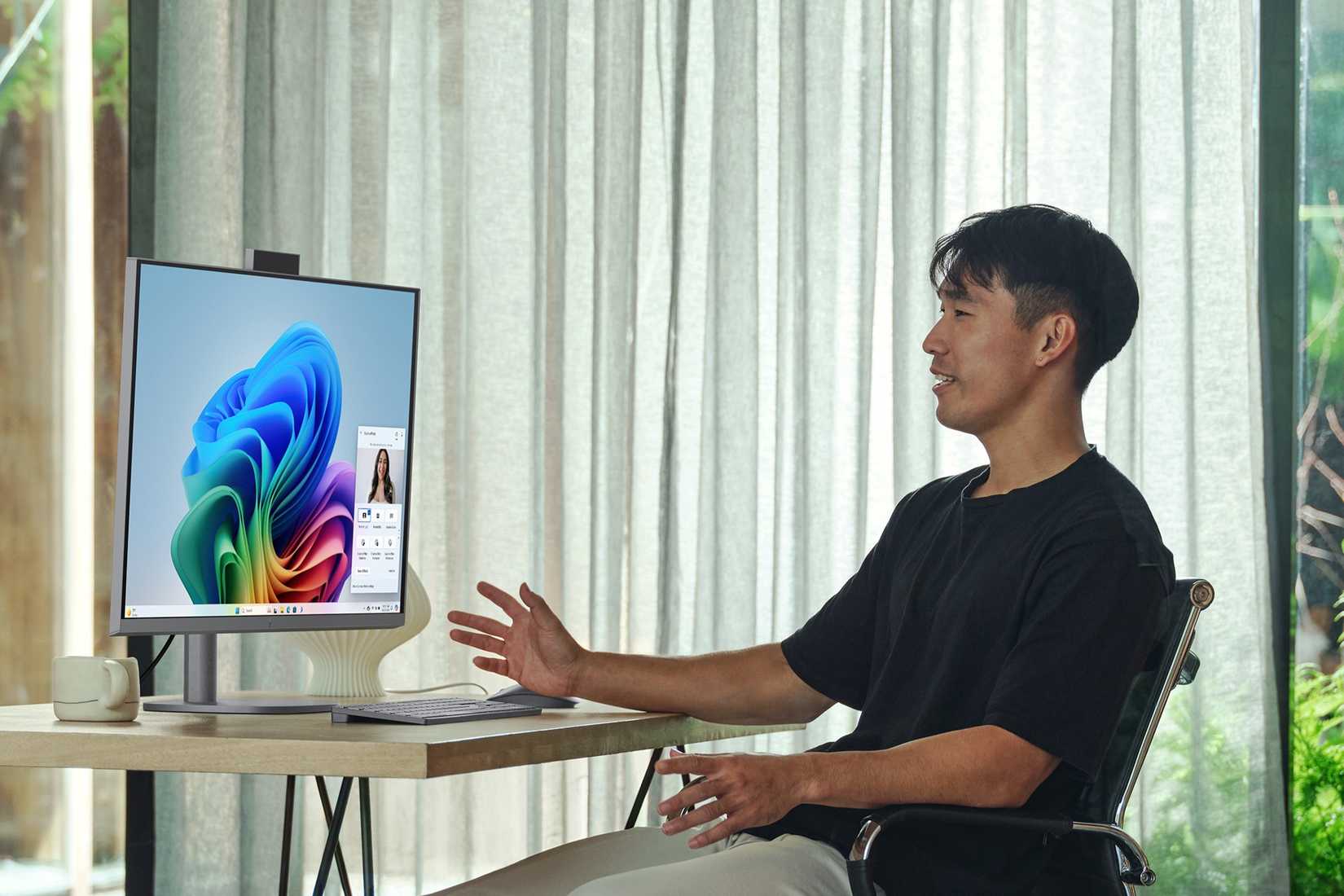 A man sitting in front of the HP OmniStudio X on a desk