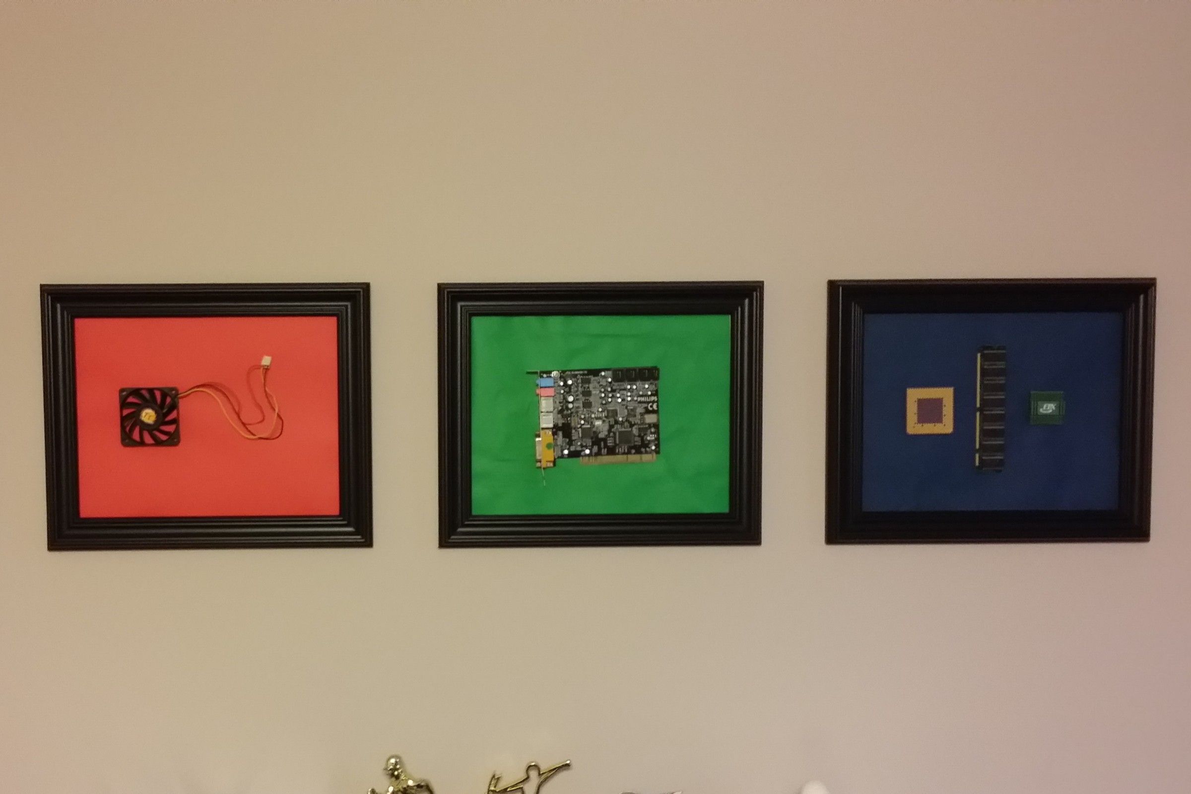 three picture frames in a row on a wall, each with different PC components inside