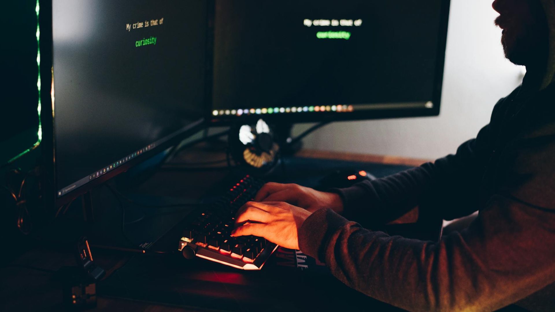 Hacker typing on a keyboard sitting in the dark