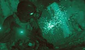 Screenshot from Call of Duty: Modern Warfare (2019) video game of armed soldier in firefight while using night vision goggles
