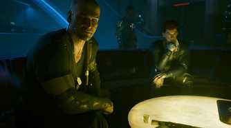 A screenshot from Cyberpunk 2077: Phantom Liberty, showing Kurt Hansen, the DLC's antagonist, sitting with the protagonist and another character at a warmly-lit table.