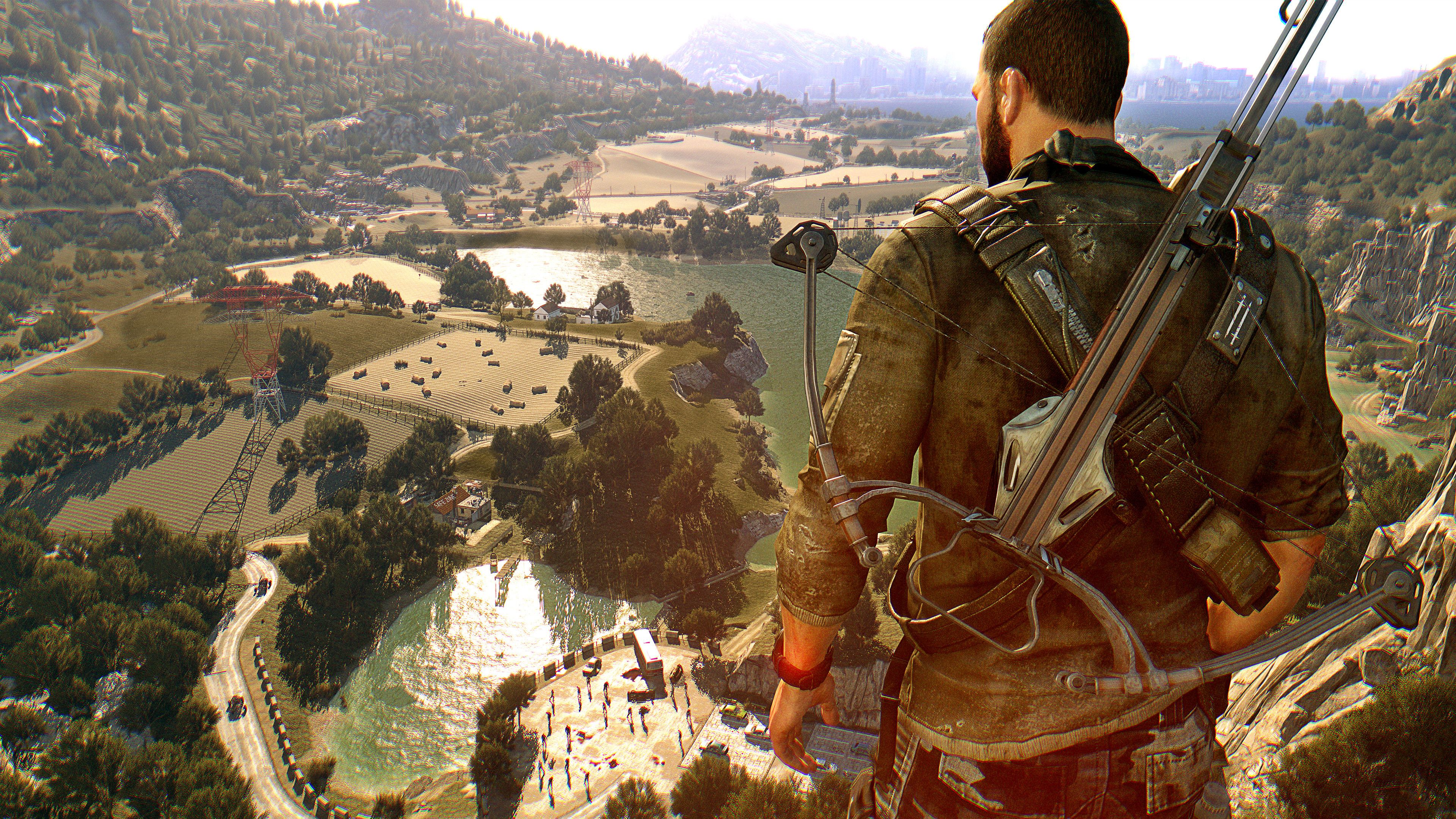 A screenshot from Dying Light: The Following, showing Kyle Crane, the protagonist, with a crossbow on his back, looking from atop a cliff at the countryside.