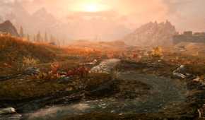 A screenshot from the game The Elder Scrolls V: Skyrim, showing a beautiful sunset as small stream of water runs through a lush field bathed in the light of the setting sun.