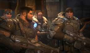 A screenshot from the game Gears of War: Ultimate Edition, showing four men in a squad wearing big, bulky armor and wielding weapons, looking at each other.
