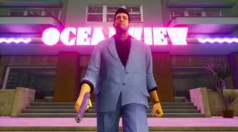 Screenshot from Grand Theft Auto Trilogy: The Definitive Edition video game of Grand Theft Auto: Vice City character walking with a pistol, with a bright neon sign behind them