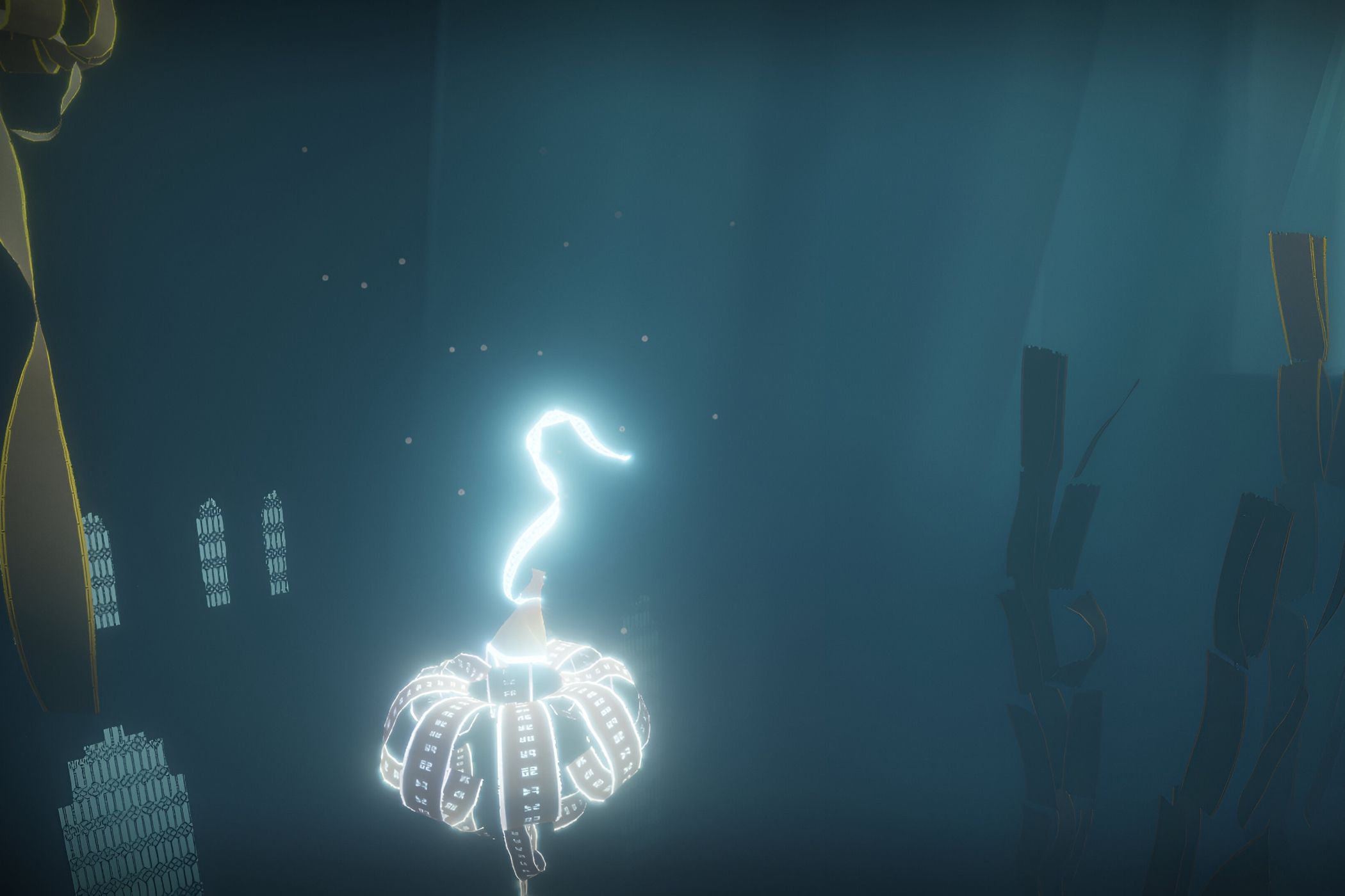 A screenshot from the game Journey, showing the protagonist's robes glow as they float through a dark, blue, environment.