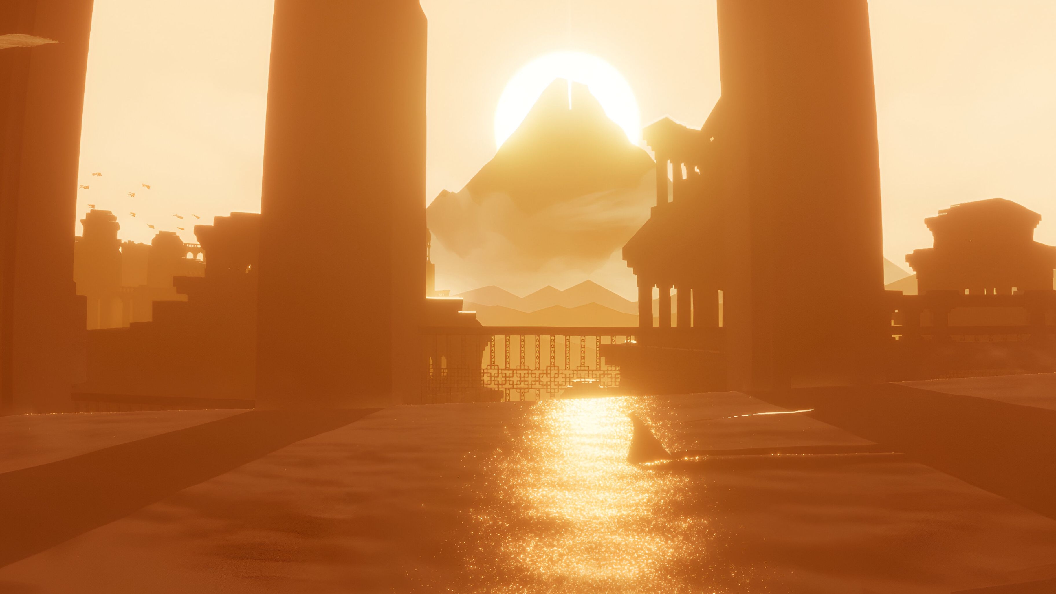 A screenshot from the game Journey, showing a beautifully lit desert landscape as the sunlight turns everything golden, and the protagonist walks through sand.