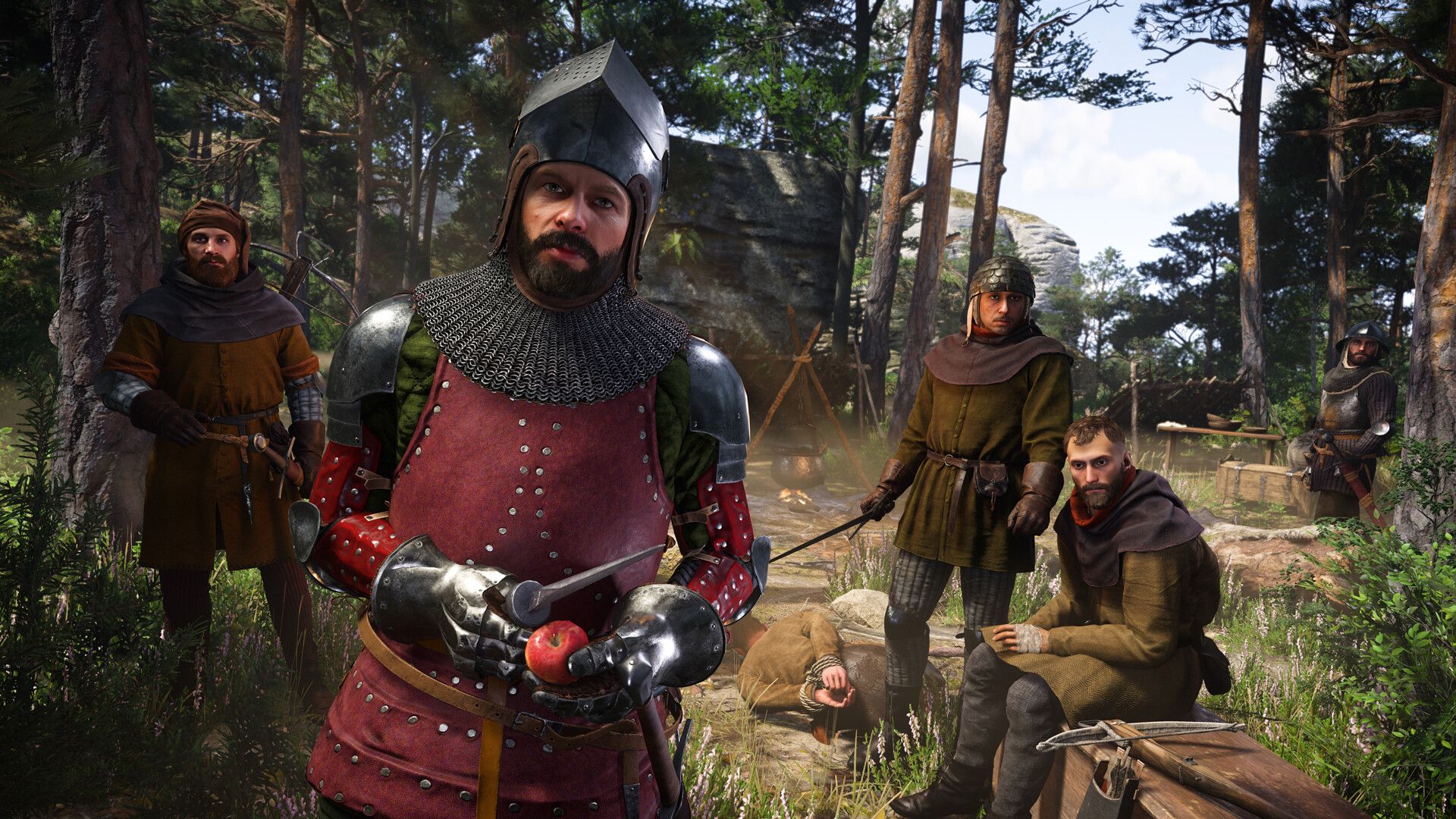 six men at a camp in the woods in medieval setting, one dressed in heavy armor.