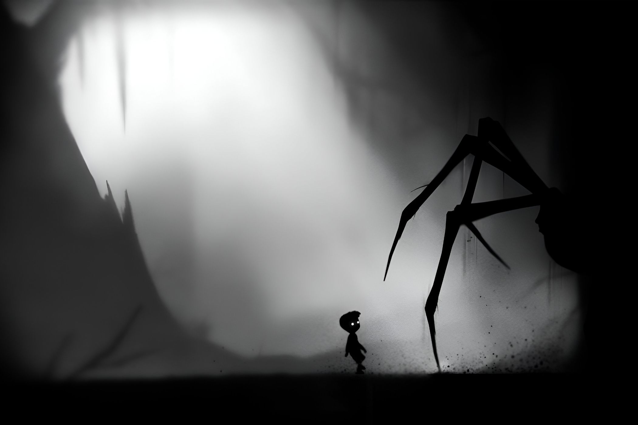 A screenshot from the game Limbo, showing a monochromatic art style while the protagonist faces down a huge spider.