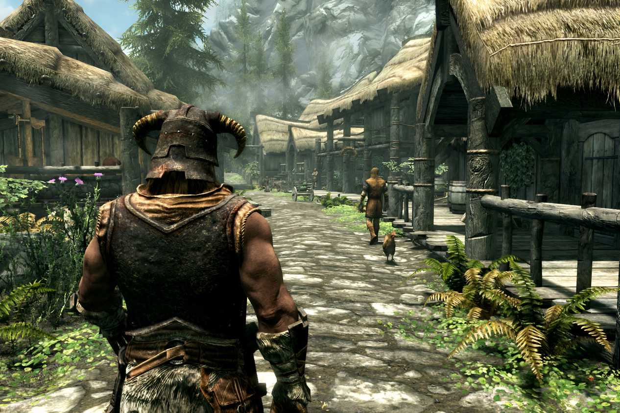 A screenshot from the game The Elder Scrolls V: Skyrim, showing a muscular man with a horned helmet walking down a lush village street.