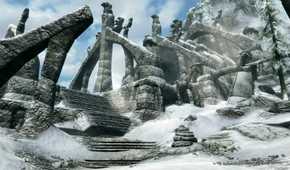 A screenshot from the game The Elder Scrolls V: Skyrim, showing ruins of a huge structure, covered in parts in snow.
