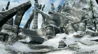 A screenshot from the game The Elder Scrolls V: Skyrim, showing ruins of a huge structure, covered in parts in snow.