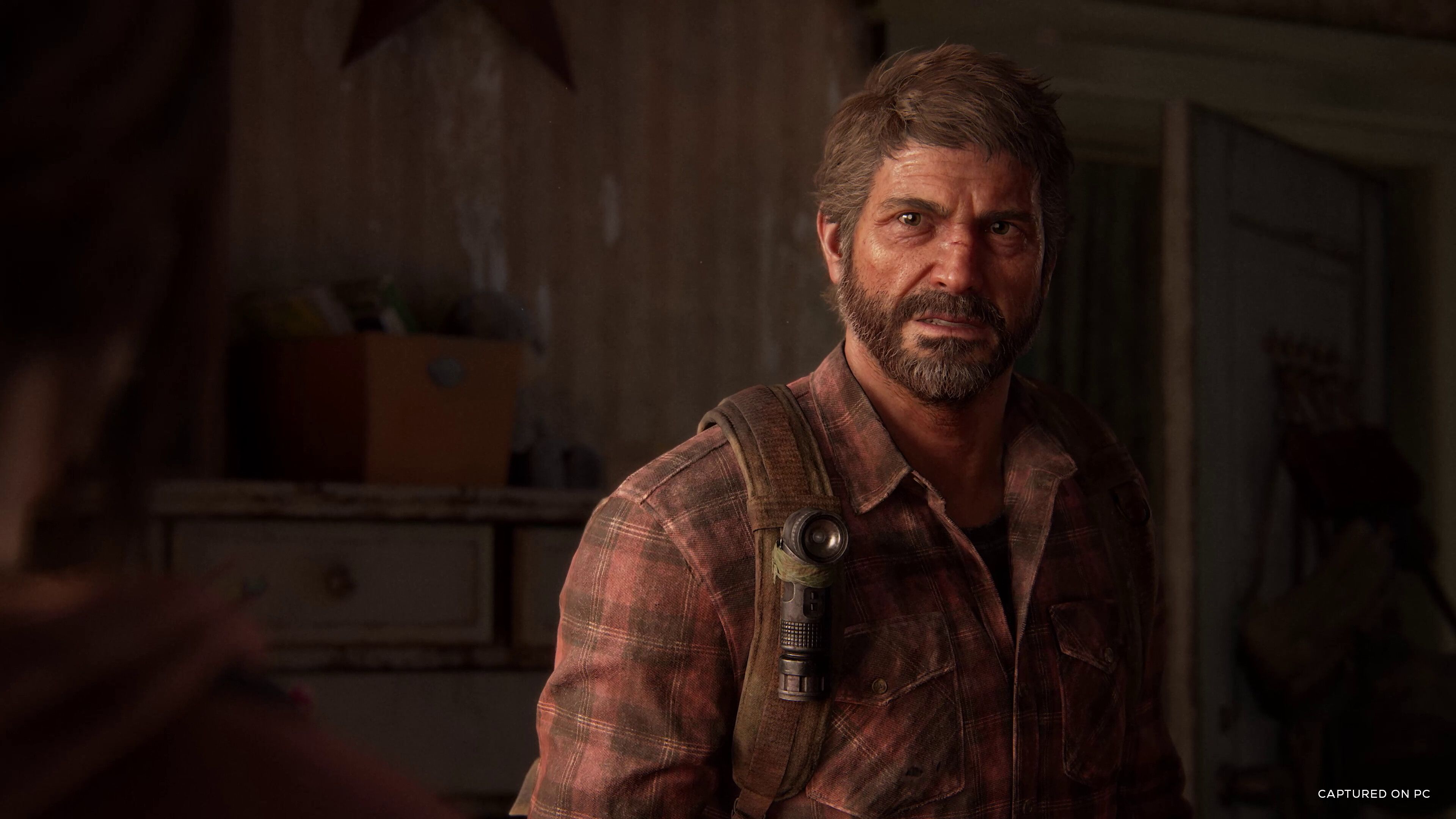 Screenshot from The Last Of Us Part I video game on PC of main character Joel in dilapidated bedroom