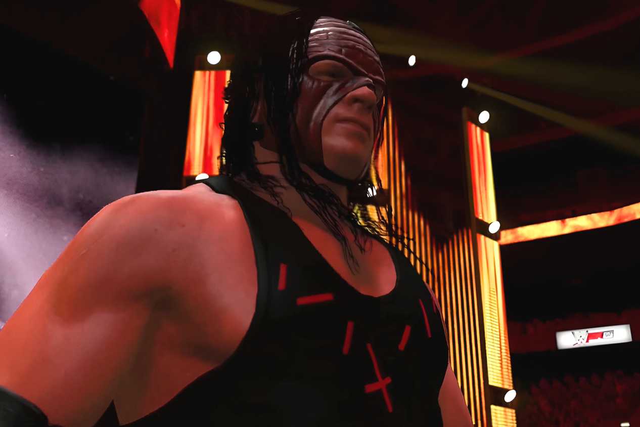 A WWE 2K15 screenshot showing Kane, wearing a red and black vest and a red mask, make his entrance.