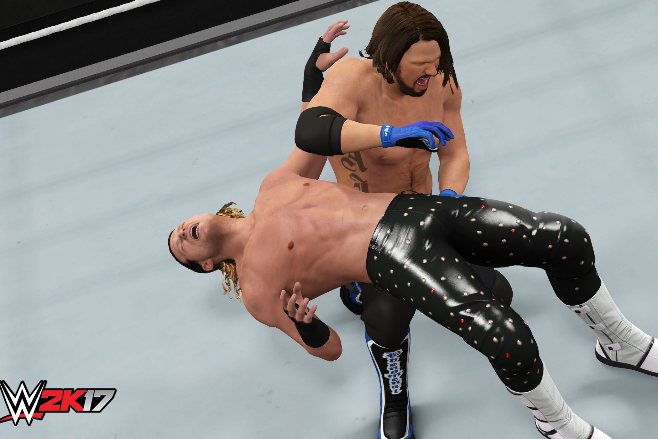A screenshot from WWE 2K17, showing superstar AJ Styles hit a backbreaker on Dolph Ziggler.
