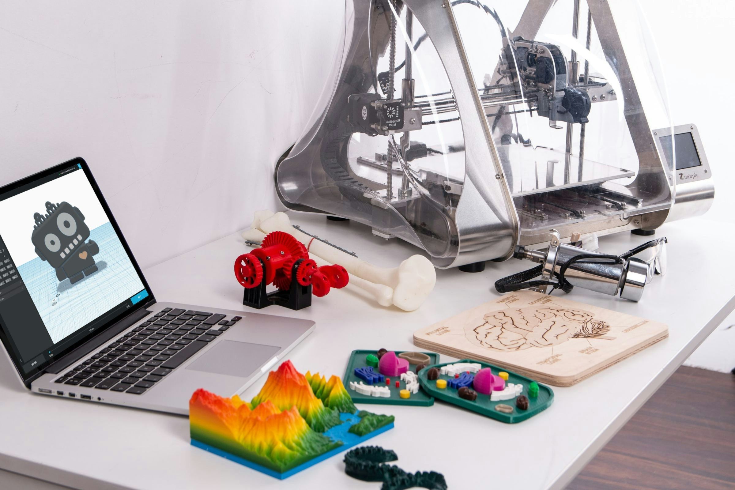 Laptop computer and 3D printer sitting on top of a white desk
