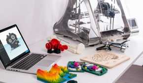 Laptop computer and 3D printer sitting on top of a white desk