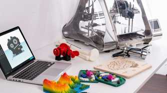 Laptop computer and 3D printer sitting on top of a white desk