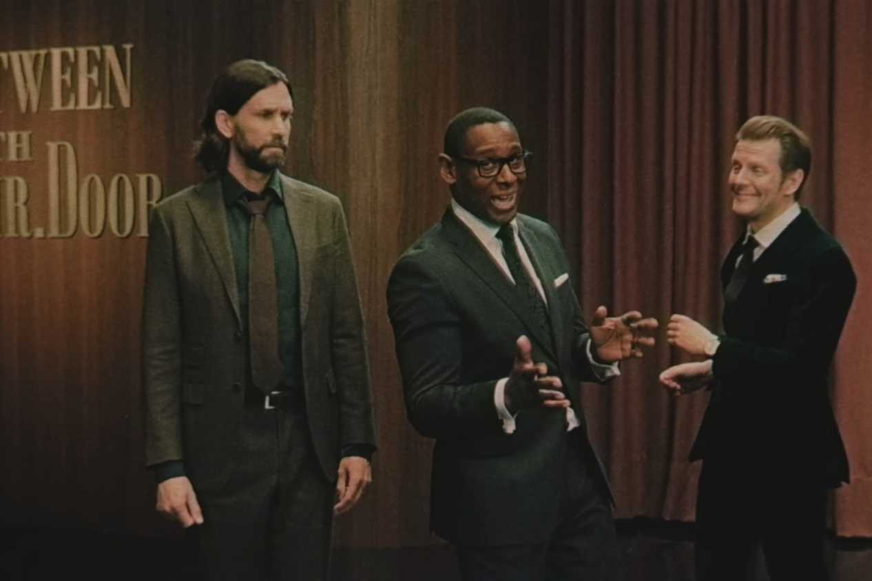 An image from the game Alan Wake II, showing three men in suits standing next to each other.