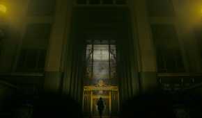 An image from the game "Alan Wake 2", showing a huge building bathed in dim yellow light.