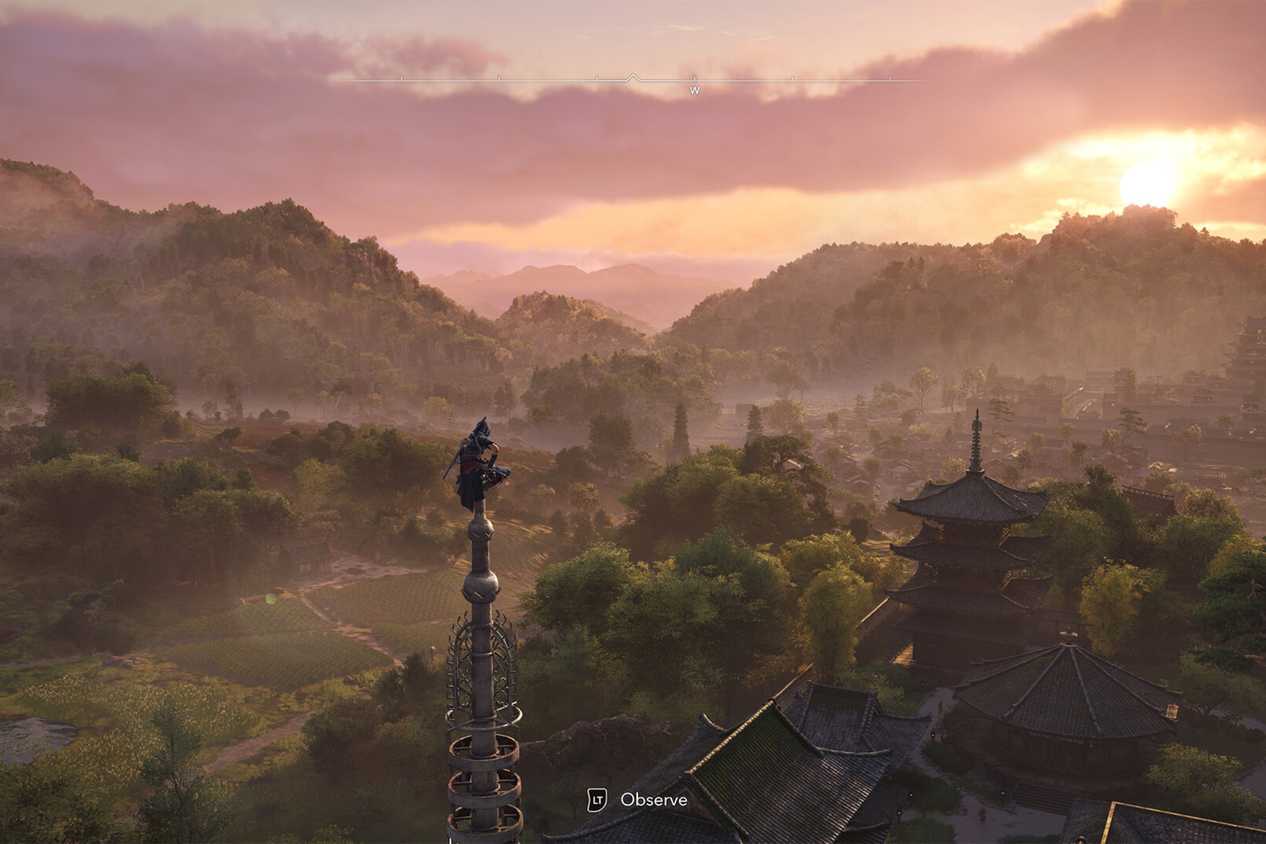 A screenshot from Assassin's Creed Shadows, showing the protagonist Naoe perched atop a tall pillar, taking in the mountainside.