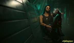 An image from the game "Cyberpunk 2077", showing a man with long hair and sunglasses sitting against a wall in a dimly-lit hallway.