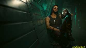 An image from the game "Cyberpunk 2077", showing a man with long hair and sunglasses sitting against a wall in a dimly-lit hallway.