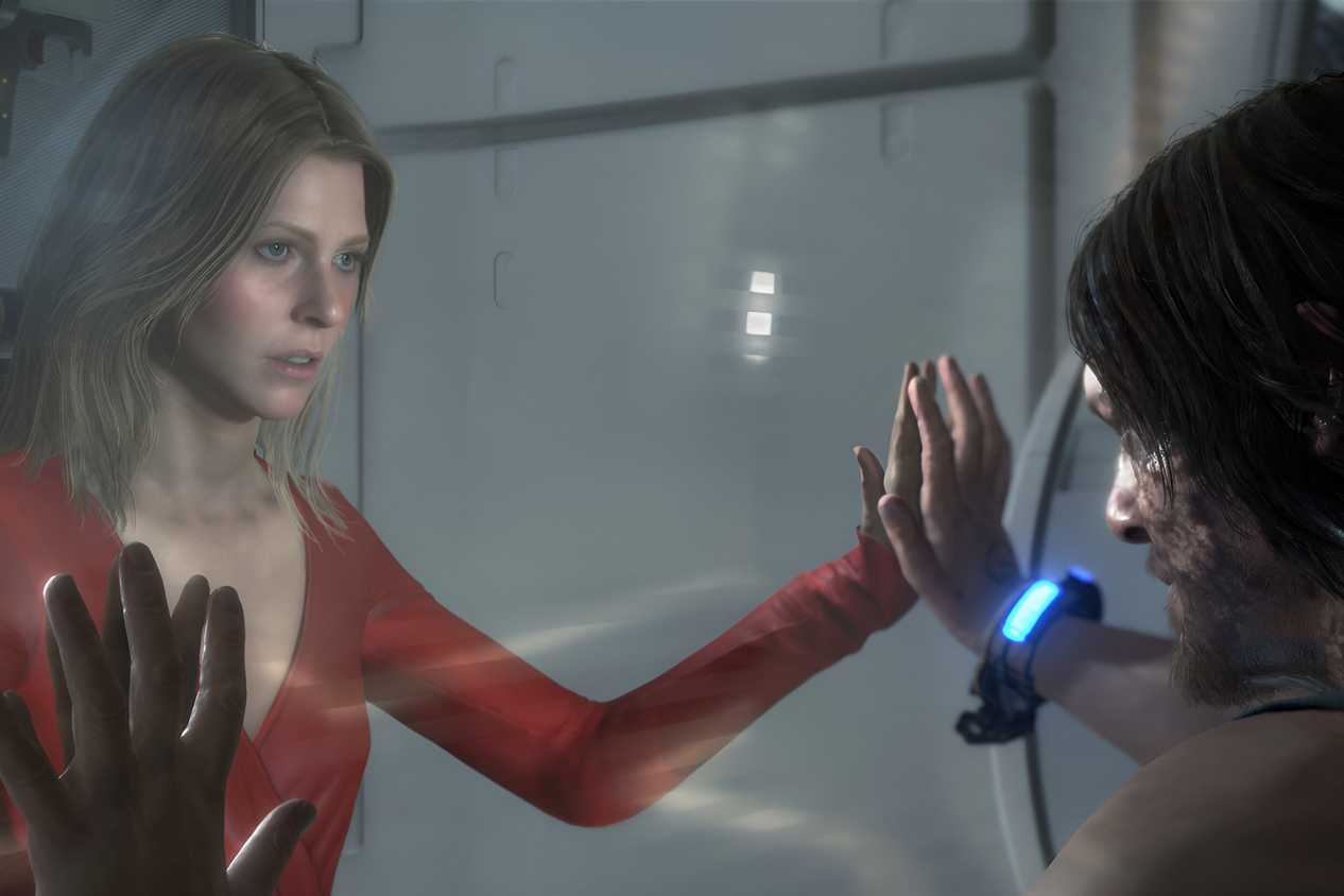 An image from the game "Death Stranding", showing a man and a woman facing each other with a glass wall between them.