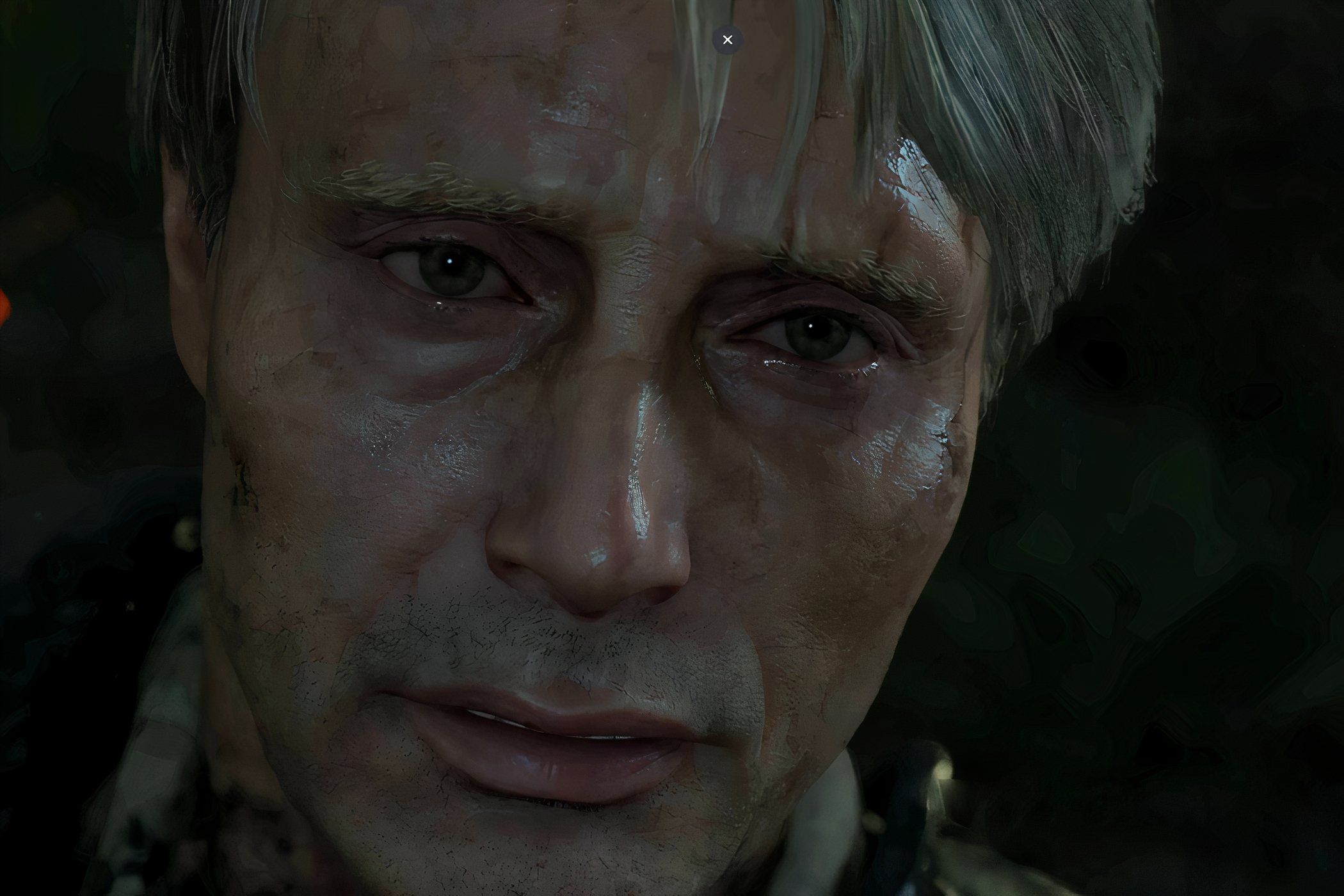 An image from the game "Death Stranding", showing actor Mads Mikkelsen covered in dirt and grime.