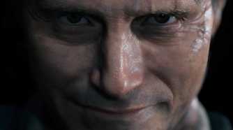 An image from the game "Death Stranding", showing a man staring into the camera with a smile on their face.