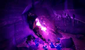 Screenshot from Deep Rock Galactic video game of purple stones illuminating dark mine with bugs all around