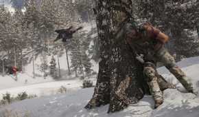 An image from Ghost Recon Breakpoint, showing a person leaning against a tree trunk.