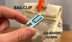 A hand holding a bag clip and another attached to the bag