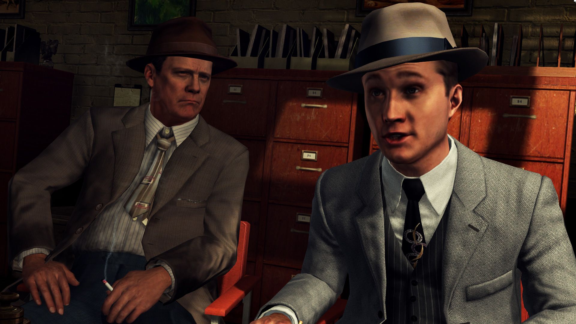 Screenshot from LA Noire video game of two men in 1940's US attire in office room talking.