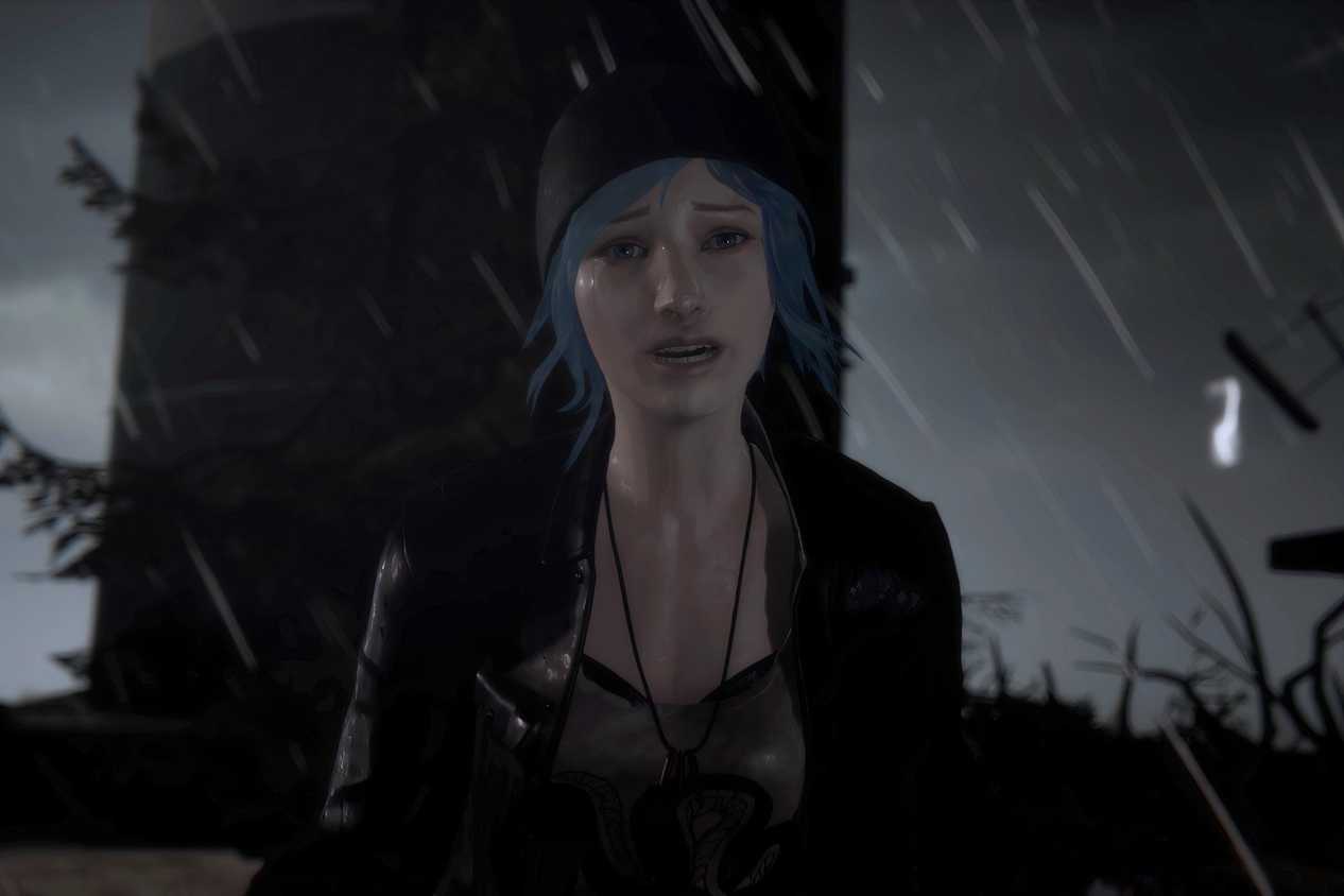 An image from the game Life is Strange, showing a blue-haired girl wearing a beanie and a jacket looking emotional as rain pours down around her.