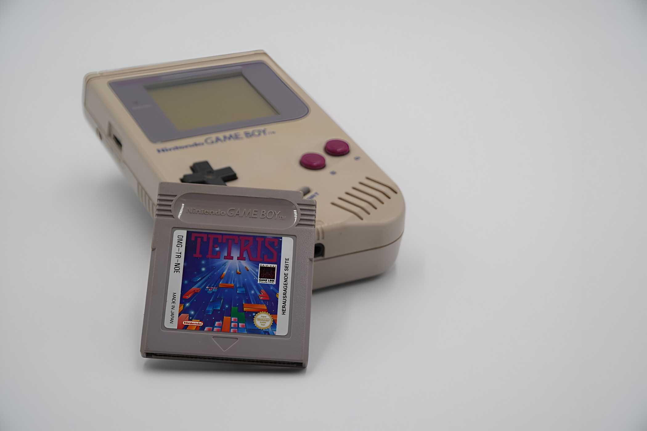 A Game Boy with a Tetris cartridge resting against it.