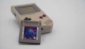 A Game Boy with a Tetris cartridge resting against it.