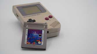 A Game Boy with a Tetris cartridge resting against it.