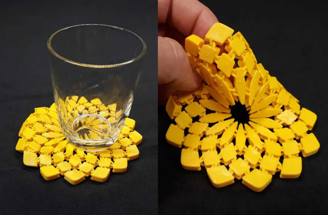 A glass on top of a 3D printed sunflower fabric and hand holding it on another side