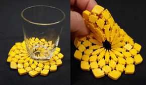 A glass on top of a 3D printed sunflower fabric and hand holding it on another side