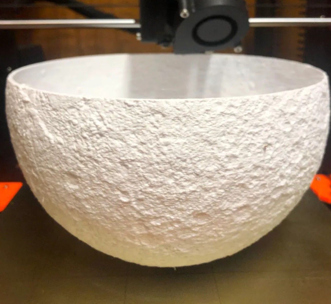 A 3D printer printing a moon design with white PLA