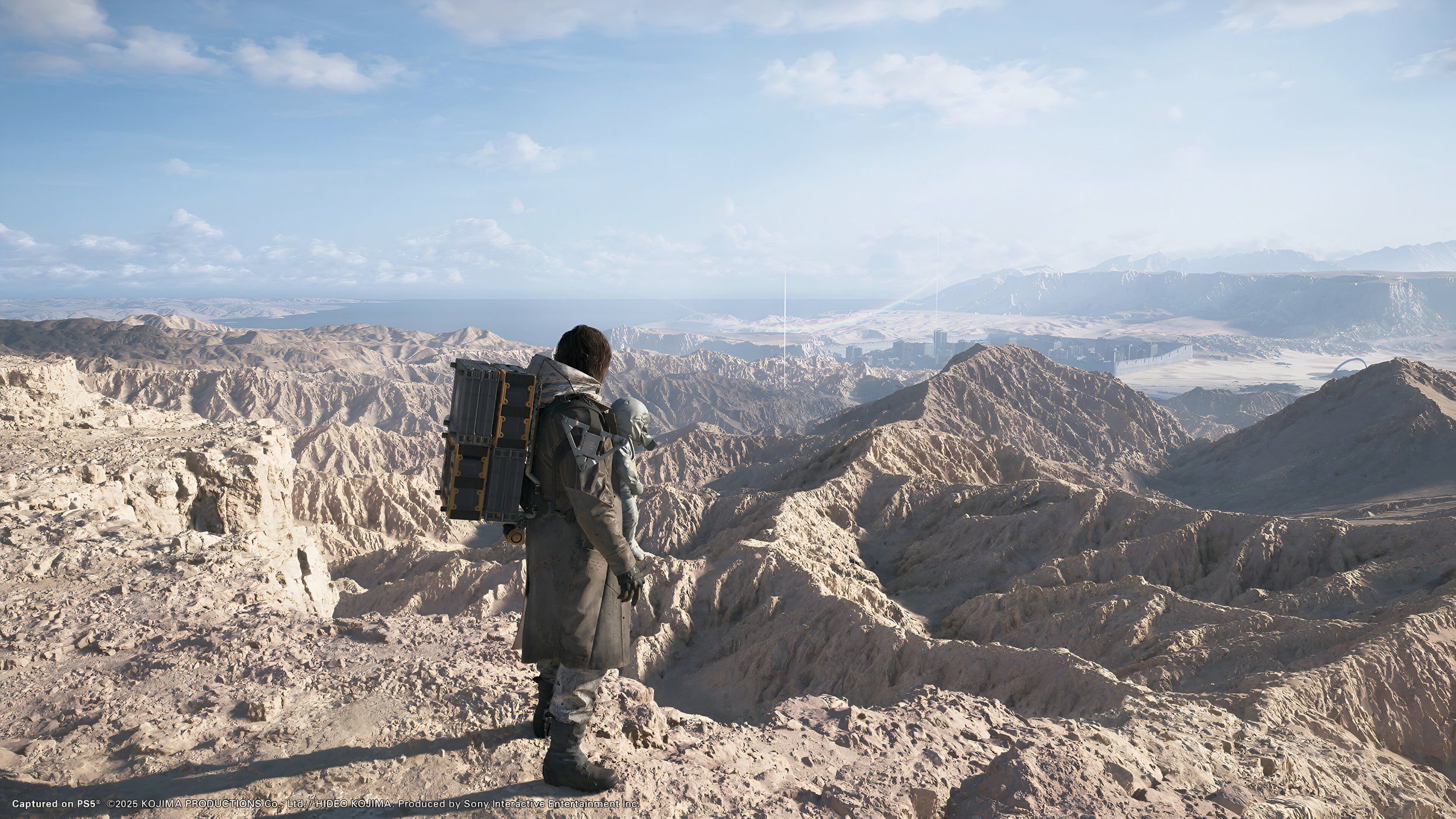An image from the game Death Stranding 2: On The Beach, showing Sam Porter Bridges looking at a huge arid desert expanding to the horizon.